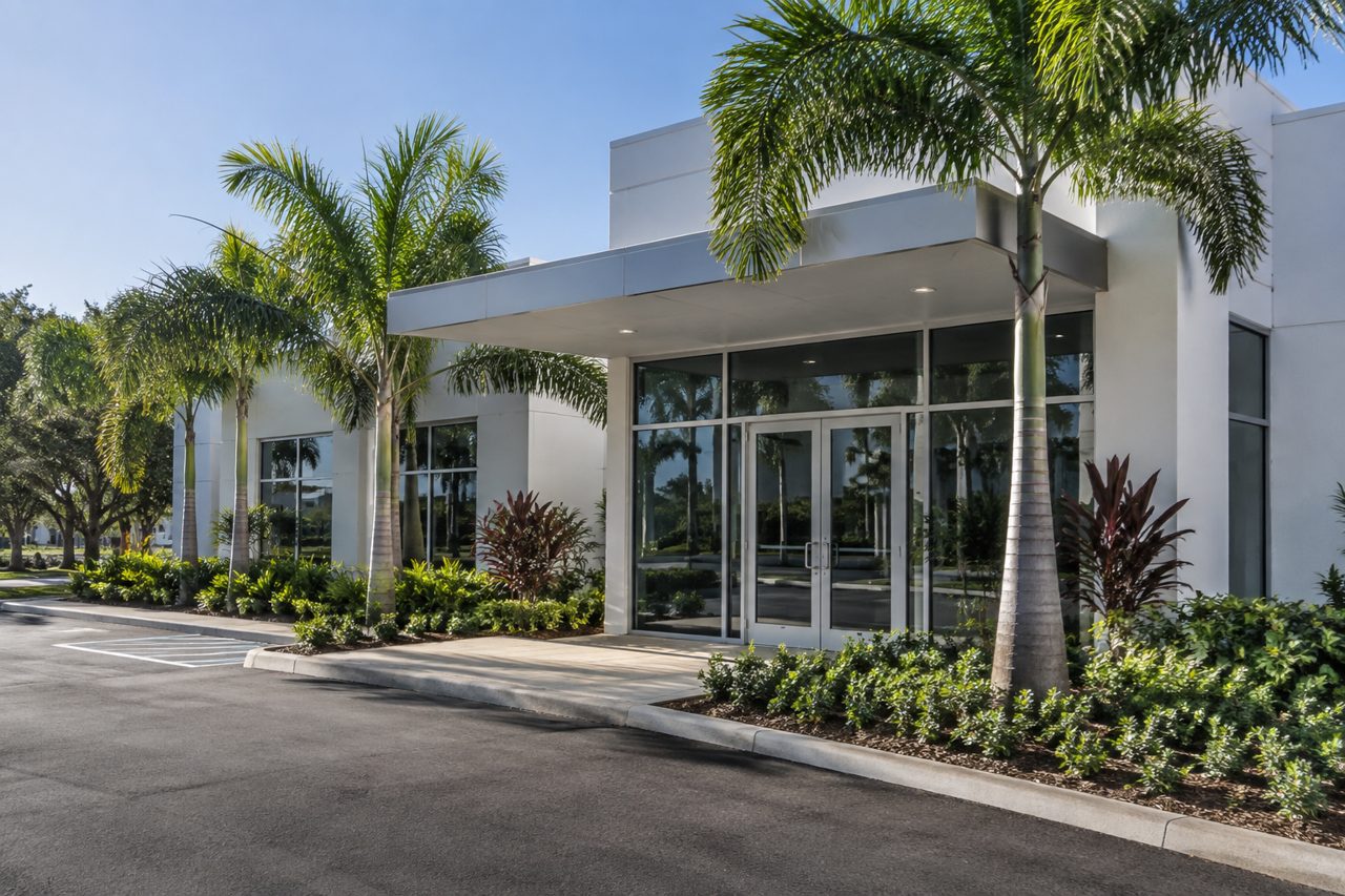 Modern single-story medical office building in Delray Beach with white facade, glass entry and palms, no signage